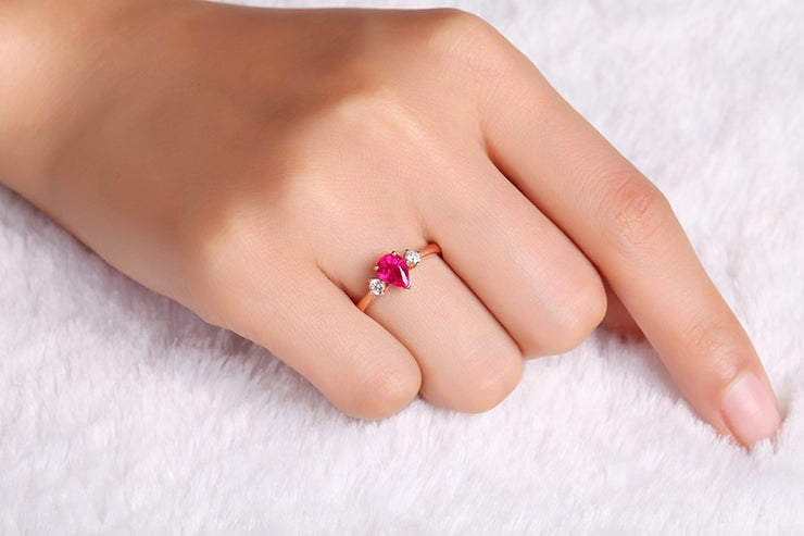 Trilogy Half Carat Pear Shape Ruby and Round Moissanite Diamond Engagement Ring in Rose Gold